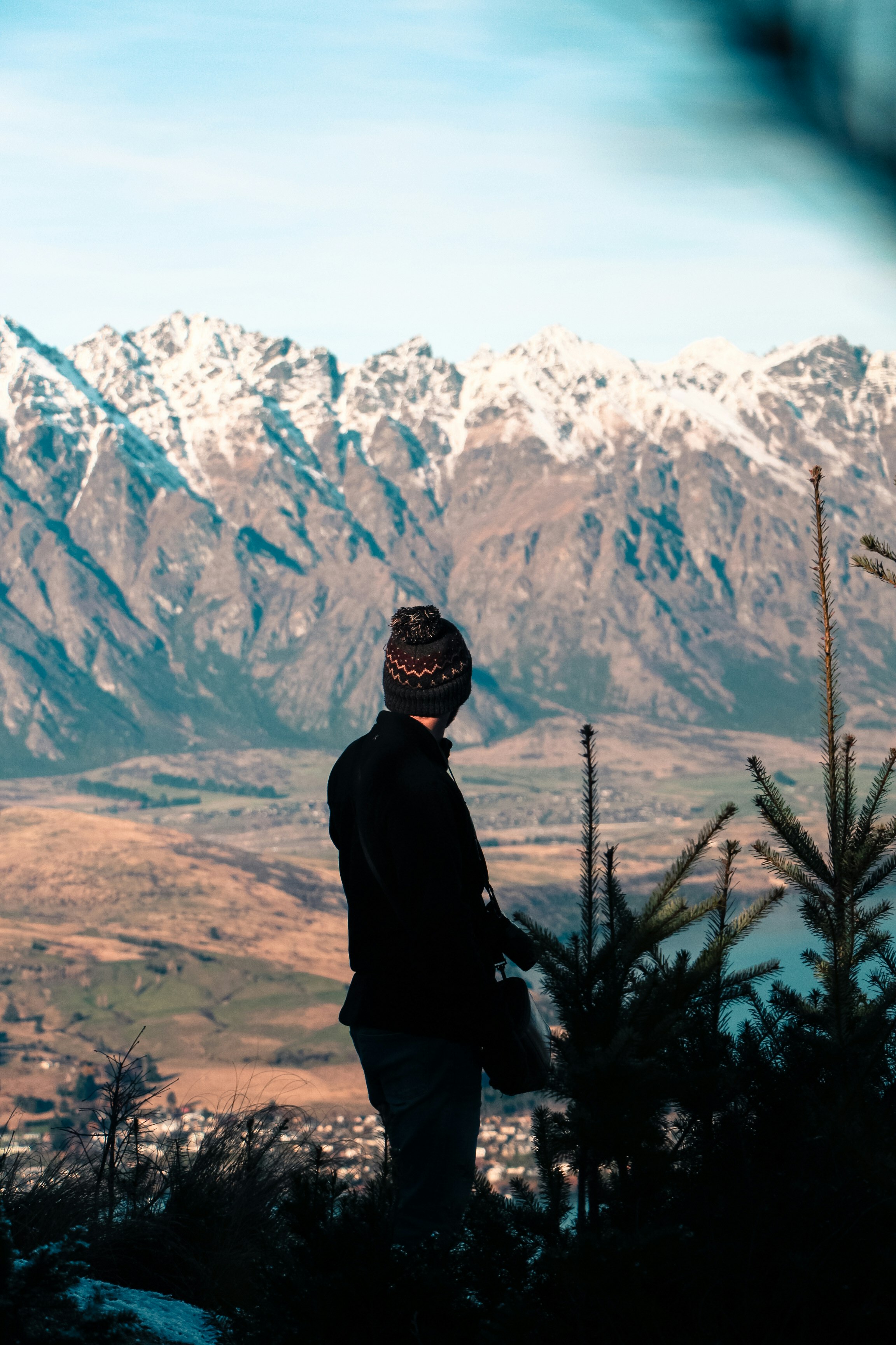 man in black jacket standing near green grass and brown mountains during daytime